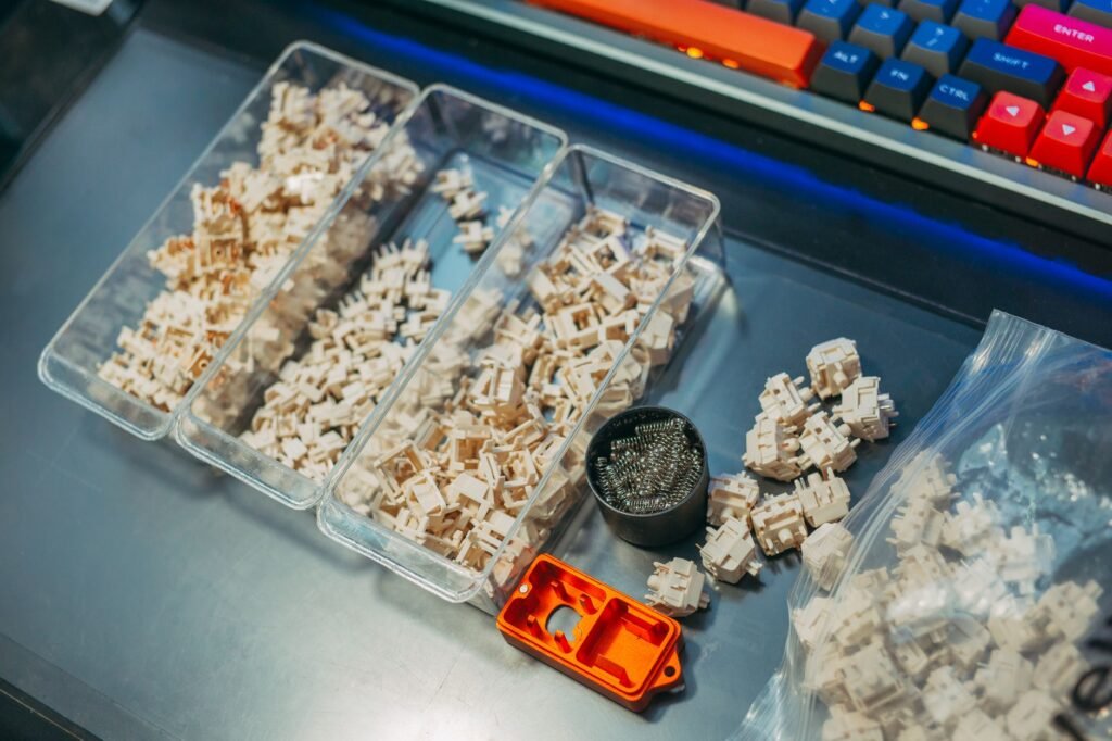 Close-up of mechanical keyboard switches and springs organized in containers on a desk setup
