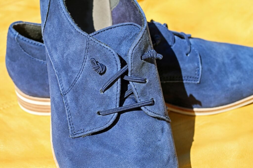Close view of blue suede lace up shoes on a yellow background