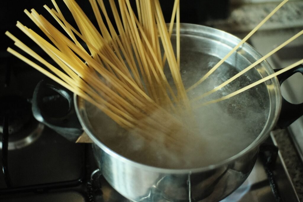 Dry spaghetti fanning out as it softens in a pot of boiling water on the stove