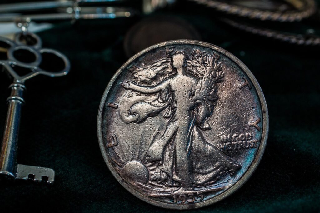 Worn silver coin standing upright beside an antique key on dark fabric