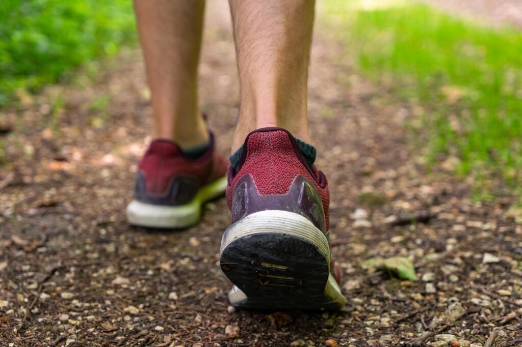 Close view of a person walking on a dirt trail in running shoes