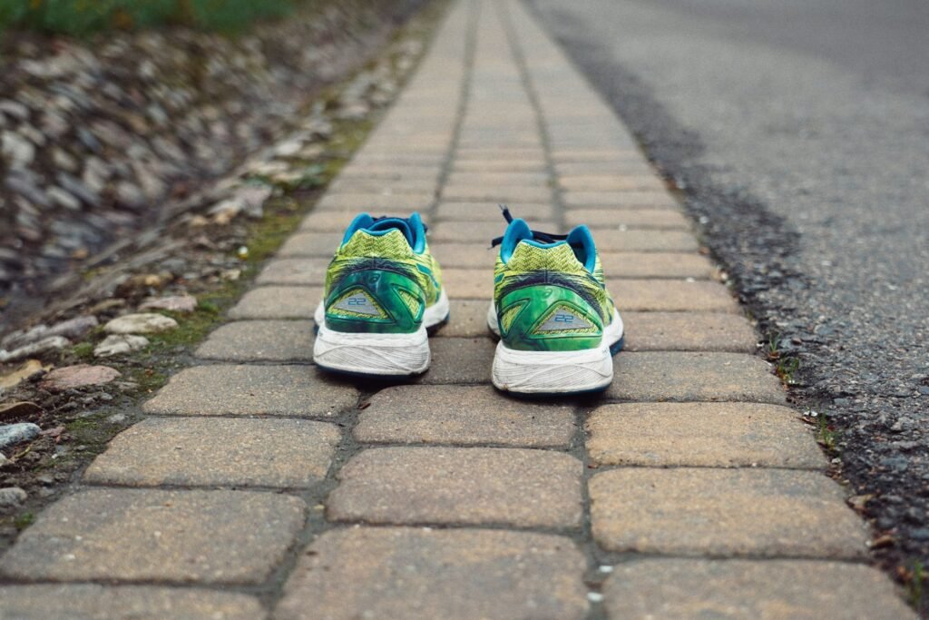 Pair of green and blue running shoes standing on a brick path