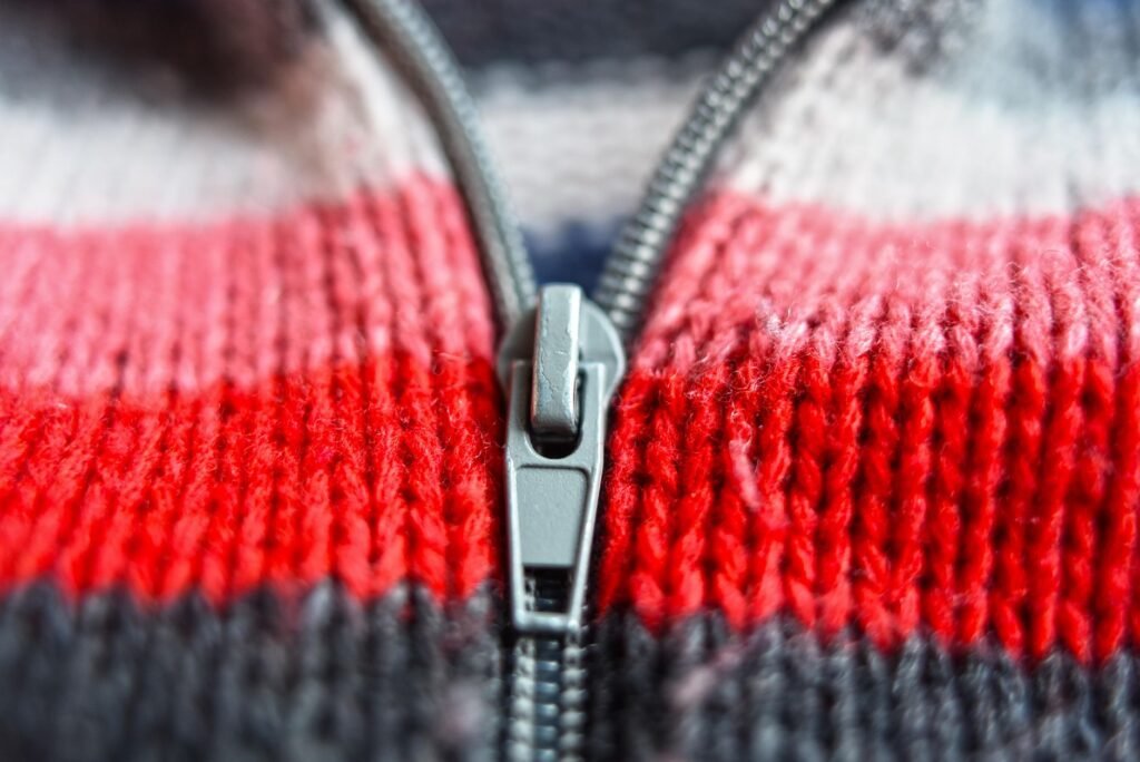 Metal zipper slider on a striped red, white and gray knit sweater