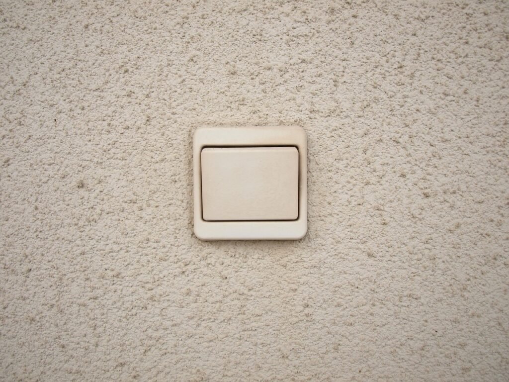 Plain beige rocker light switch mounted on a textured stucco wall
