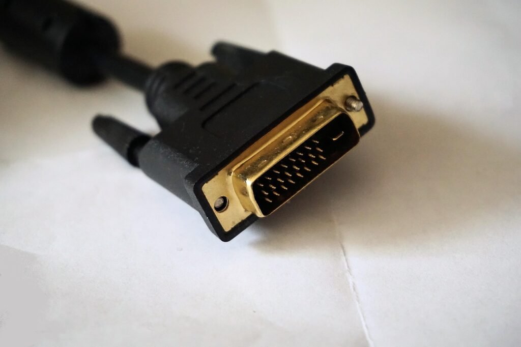 Close up of a black video cable connector with gold pins resting on white paper