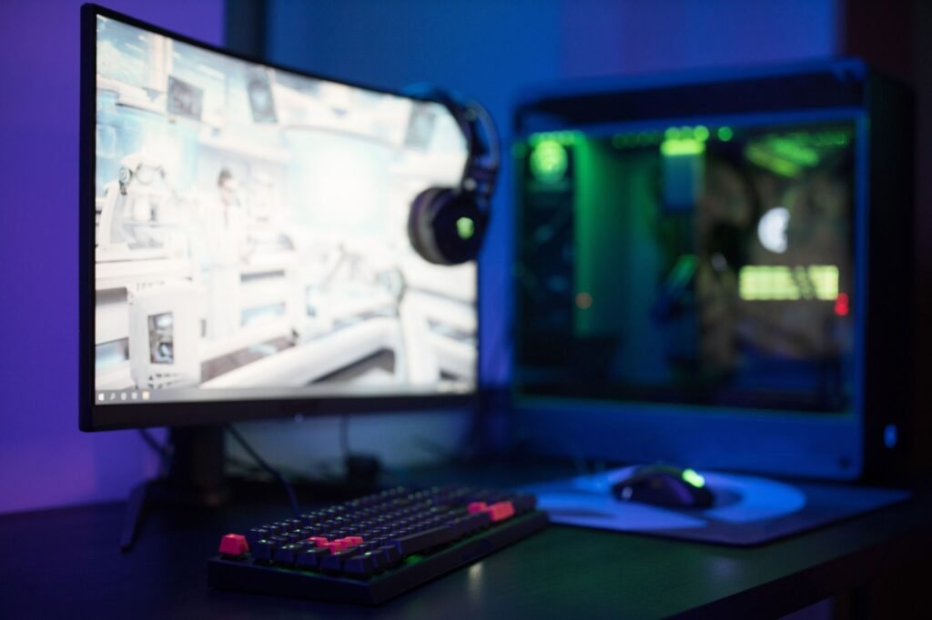 Curved gaming monitor showing a game beside a glowing desktop tower and backlit keyboard