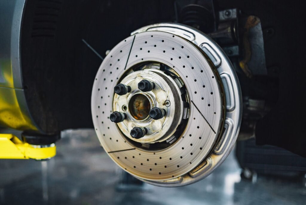 Drilled and slotted brake rotor on a wheel hub of a lifted car with the wheel removed