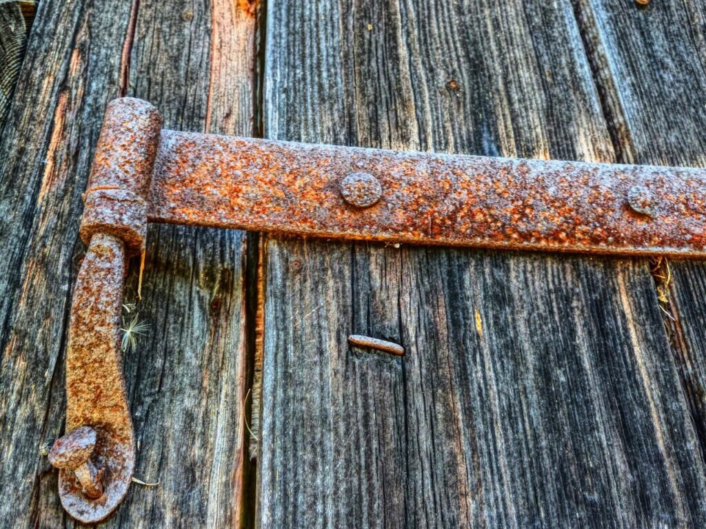 Rusty iron strap hinge bolted to a weathered gray wooden door