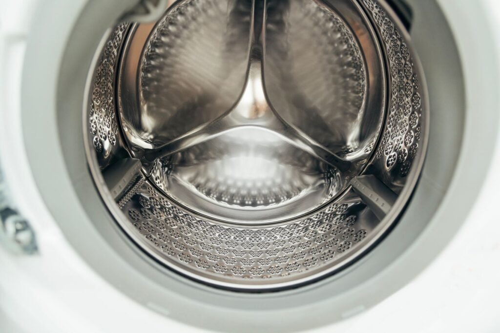 Detailed view of a clean, modern washing machine drum, showcasing shiny stainless steel interior