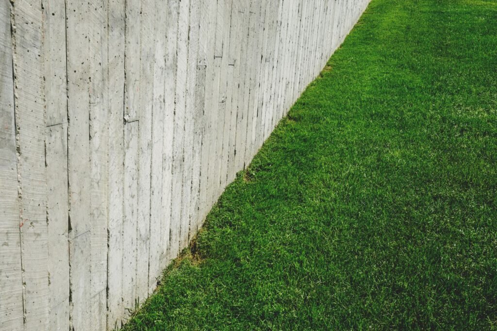 A minimalist outdoor scene featuring a wooden fence alongside a lush green lawn.