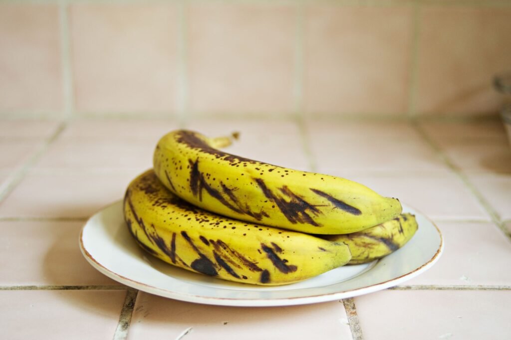 Close-up of ripe bananas with dark spots on a ceramic plate indoors. Perfect for healthy food concepts