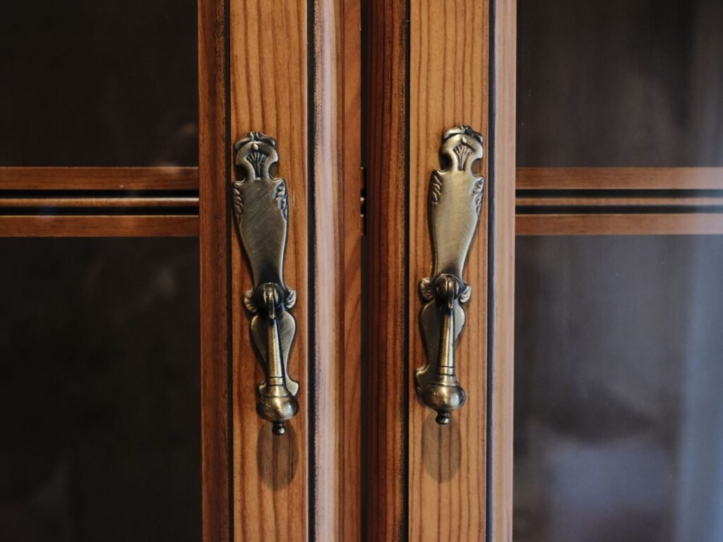 Pair of ornate metal handles mounted side by side on wooden cabinet doors
