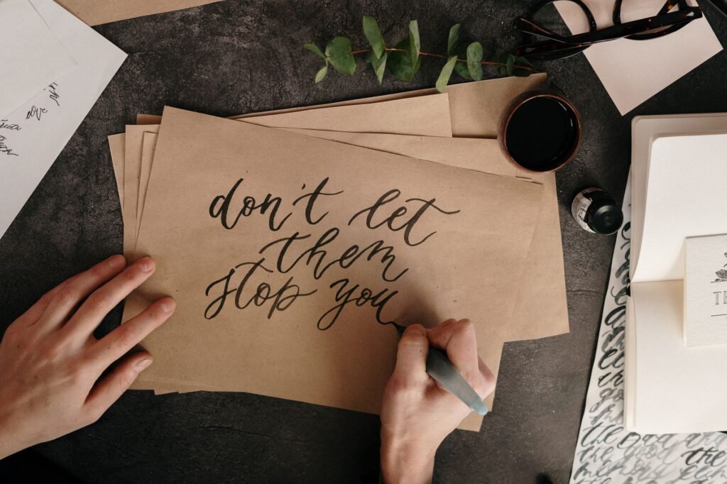 Hand writing motivational quote on textured paper with calligraphy tools.