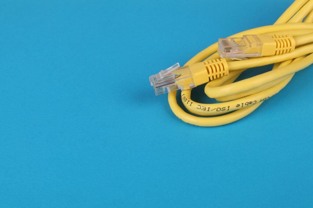 Coiled yellow network cable with a clear plug resting on a bright blue surface