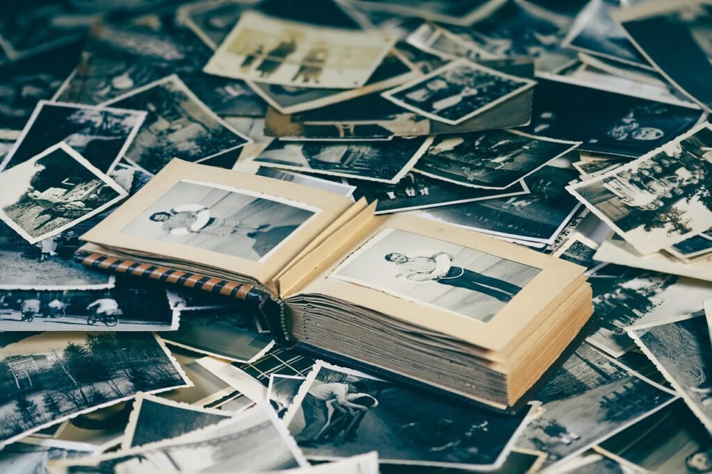 Scattered old black and white photographs around an open vintage photo album