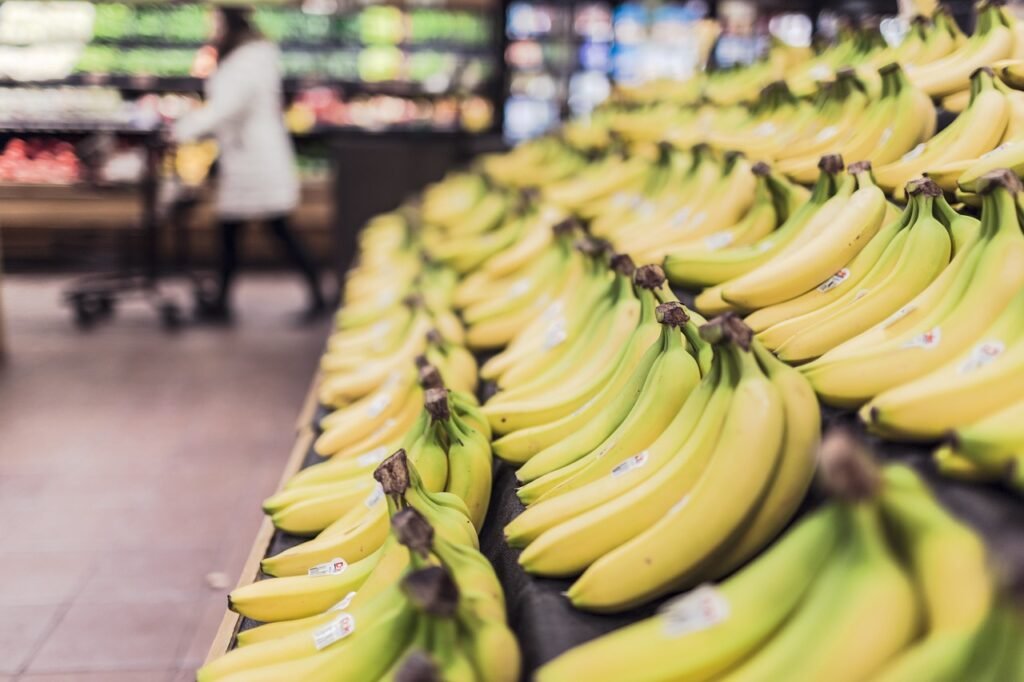 Rows of ripe yellow bananas stacked on a grocery store produce display