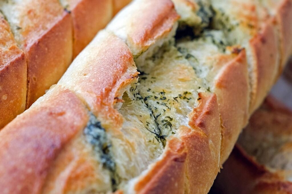 Close view of baked garlic bread with melted herb butter spread across the golden crust