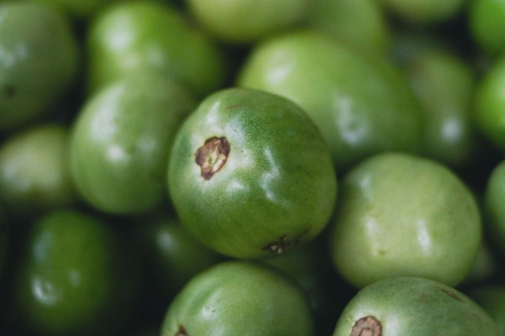 Pile of fresh green tomatillos with their husks removed, shown in close detail