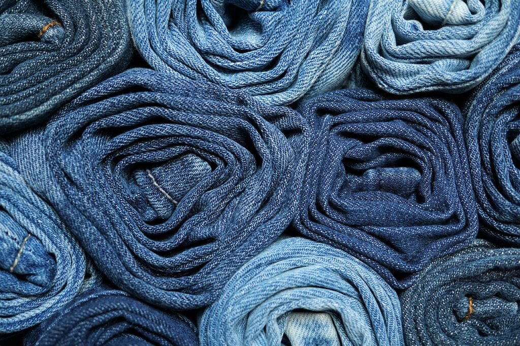 Rolled blue denim jeans stacked tightly together in varying washes