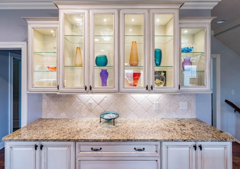Cream painted kitchen cabinets with glass doors above a granite countertop