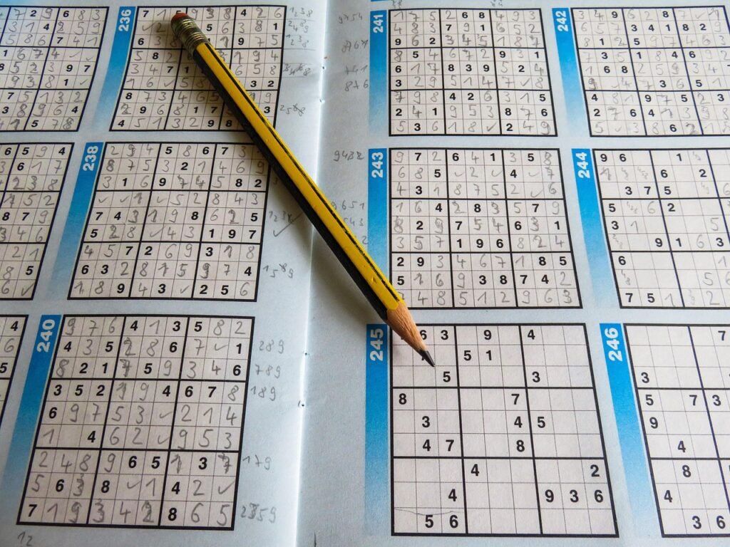 Partially filled sudoku puzzles in a puzzle book with a yellow pencil