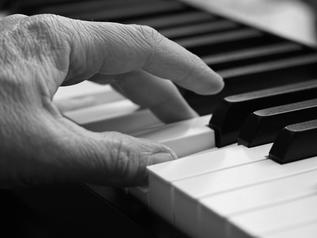 Black and white close up of a hand pressing piano keys
