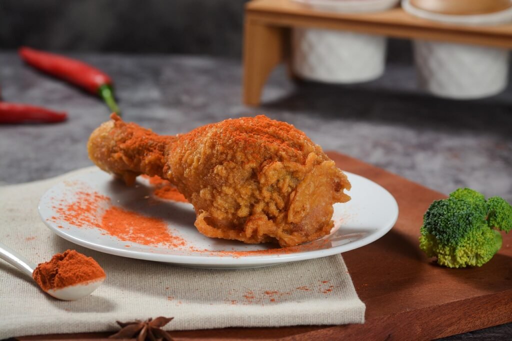 Crispy fried chicken drumstick on a white plate dusted with red spice
