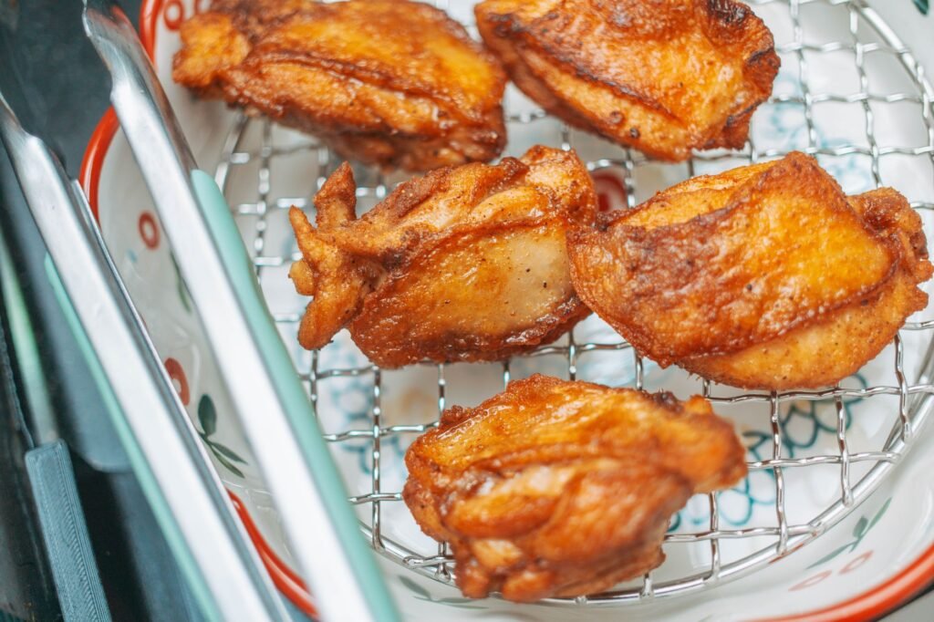 Golden fried chicken pieces resting on a wire rack