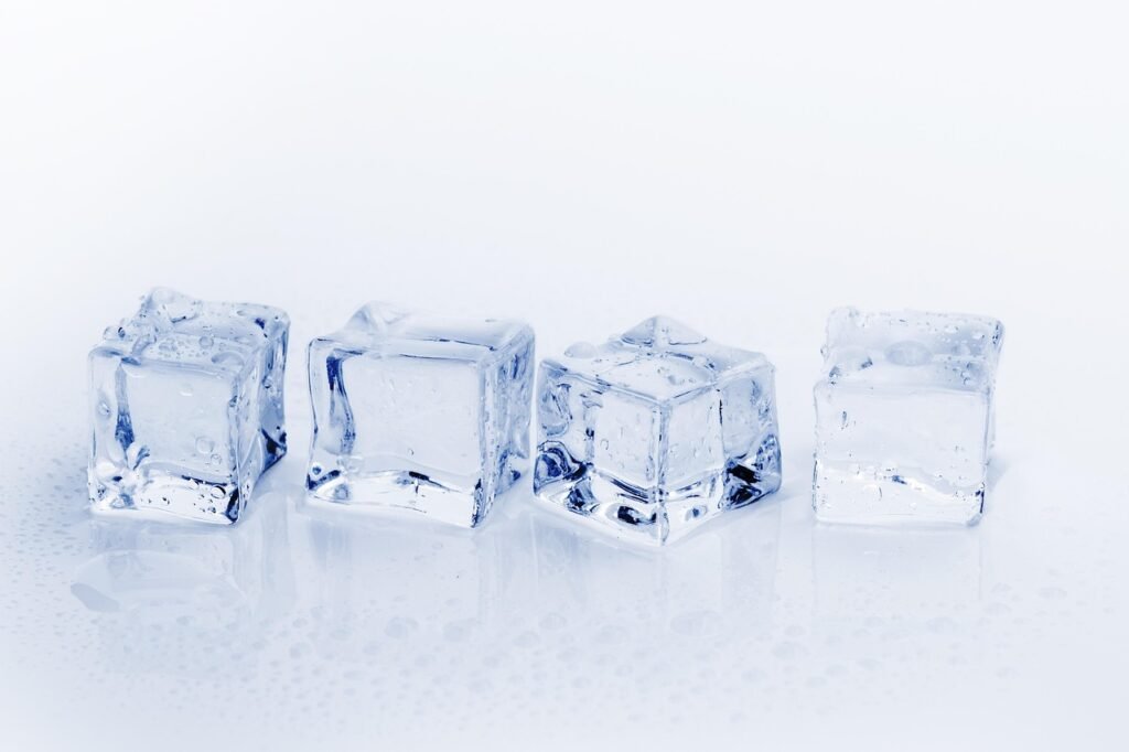 Four clear ice cubes lined up in a row on a white surface