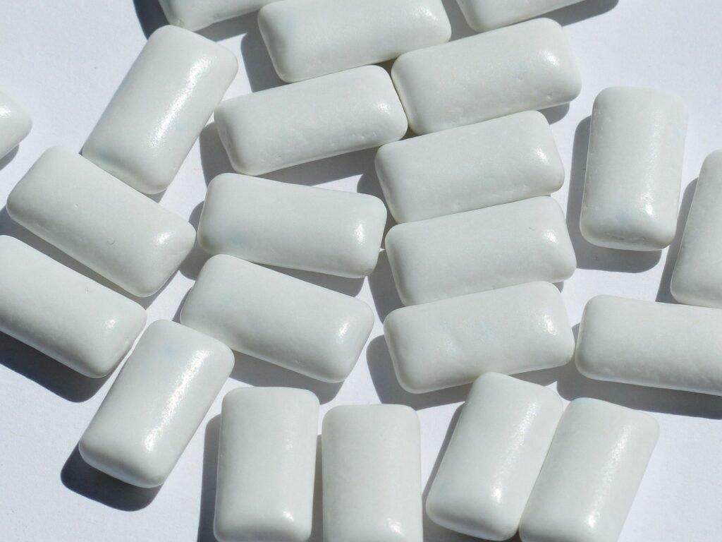 Pile of white rectangular chewing gum pellets scattered on a light surface
