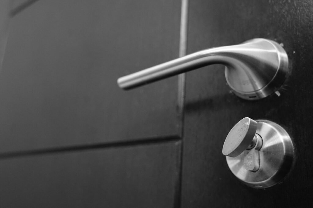 Black and white photo capturing a sleek stainless steel door handle with a focus on style and security