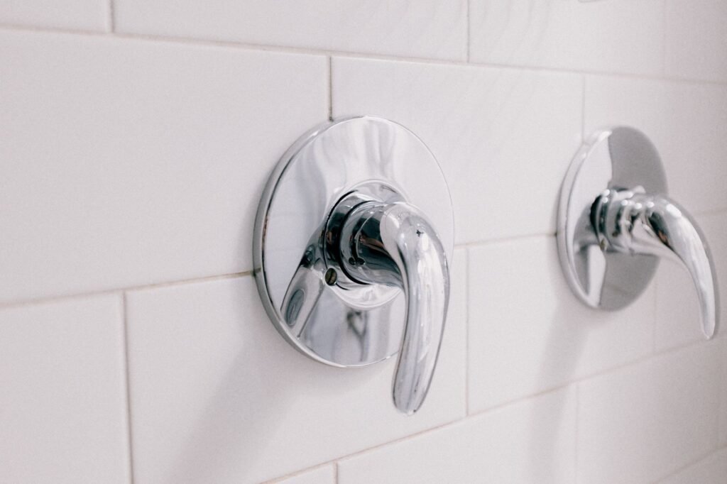 Chrome single handle shower valves mounted on a white tiled wall