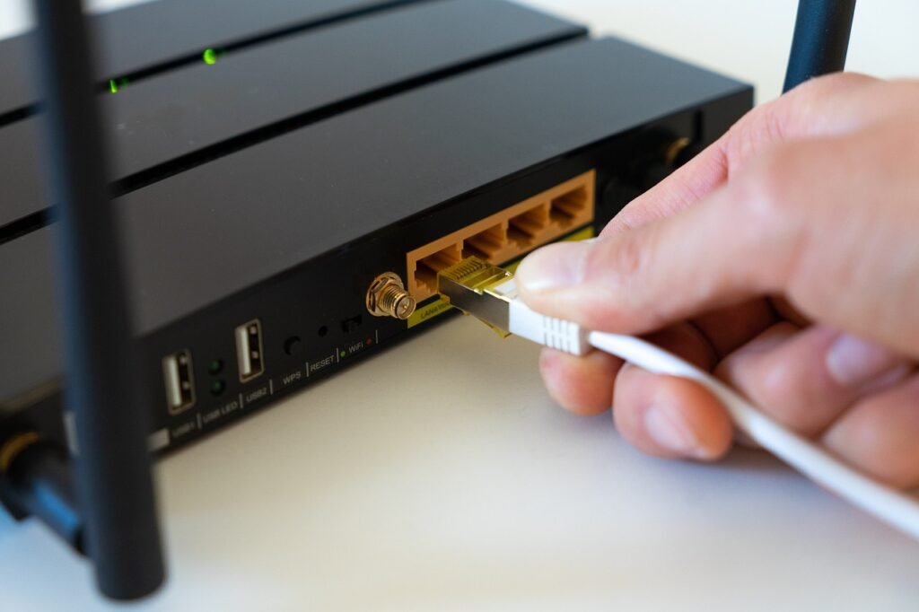 Hand plugging a white ethernet cable into the yellow port on a black router