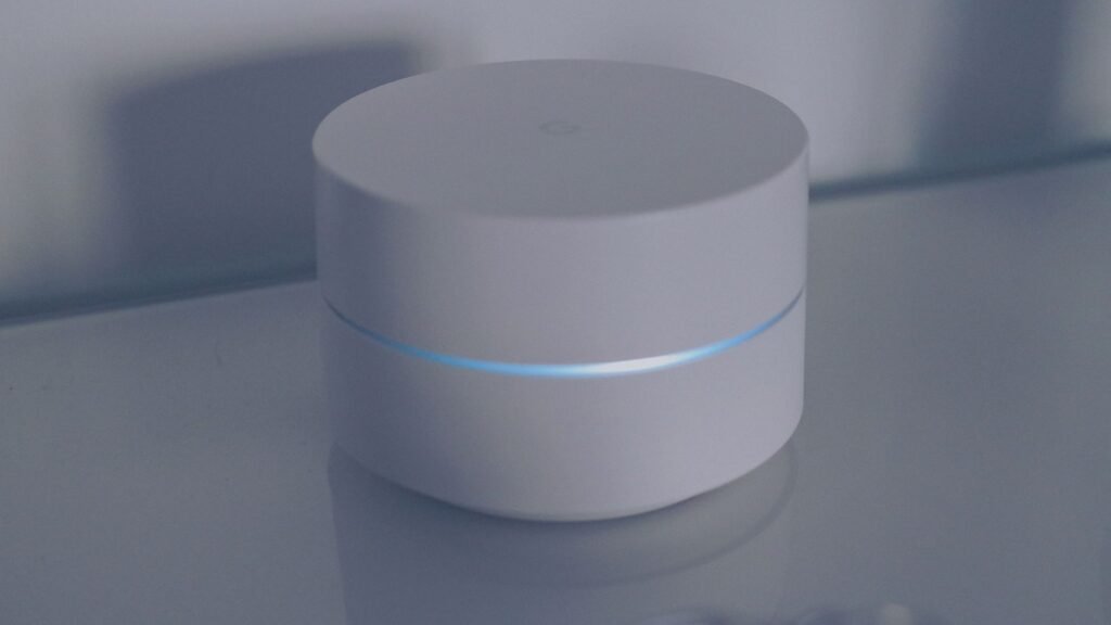 White round wireless mesh router with a glowing blue light ring on a table