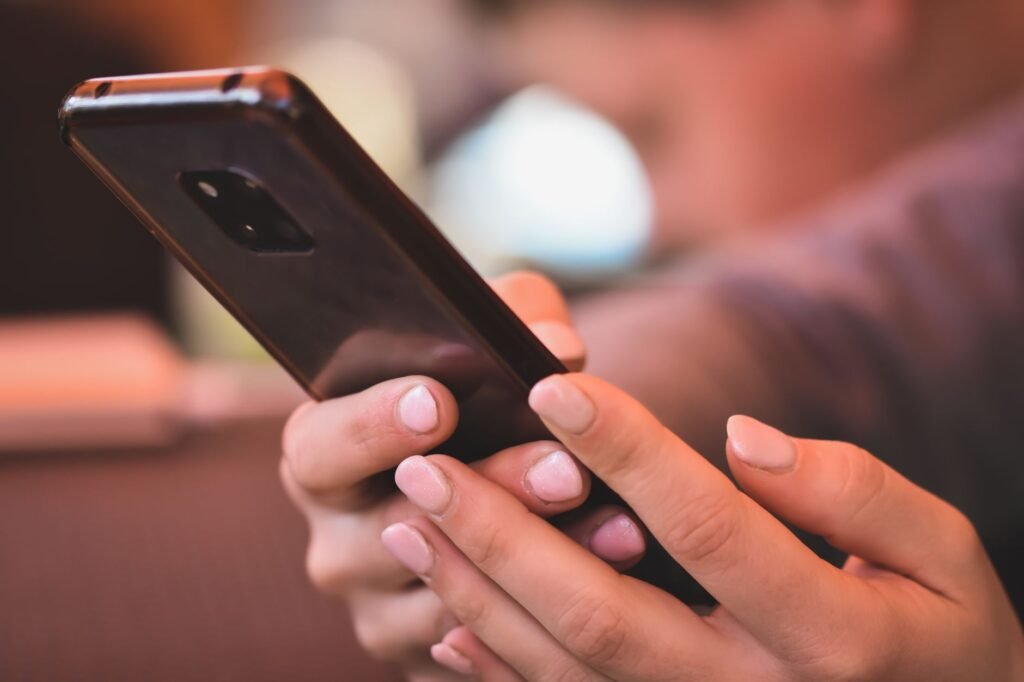 Focused shot of hands with polished nails holding a smartphone inside
