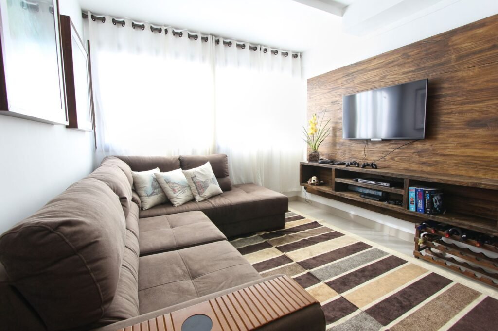 Living room with a gray sectional sofa facing a wall mounted television on a wood panel wall