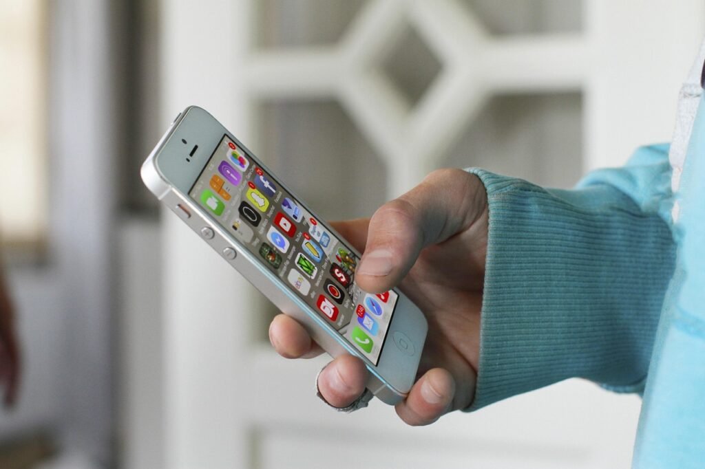 Hand holding a smartphone showing a home screen full of app icons