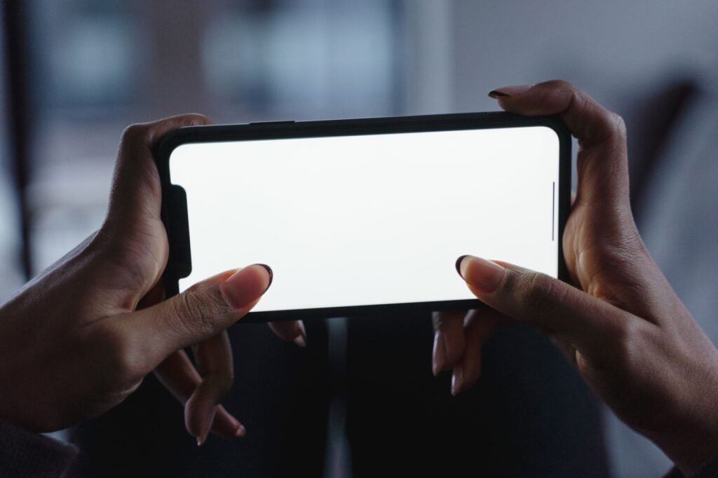 Two hands holding a smartphone sideways with a blank white screen