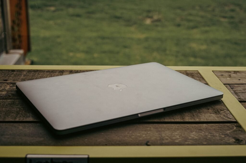 Closed silver laptop resting on a weathered wooden table outdoors
