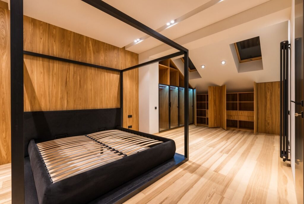 Modern black bed frame with bare wooden slats in a bright room with wood floors