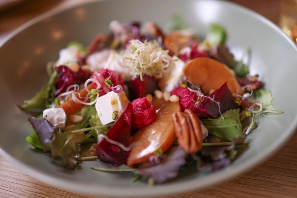 A colorful salad featuring mixed greens, goat cheese, pecans, and vibrant beets