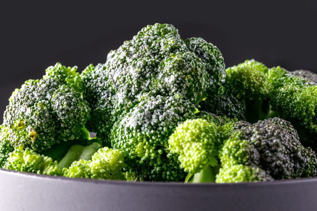 Close-up of fresh green broccoli florets in a bowl with a dark backdrop.
