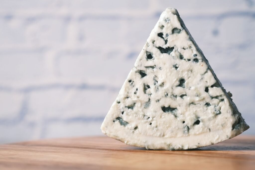 A detailed close-up of a creamy stilton cheese resting on a wooden surface, emphasizing texture.
