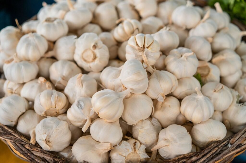 High-angle view of fresh garlic bulbs piled in a basket at a market stall