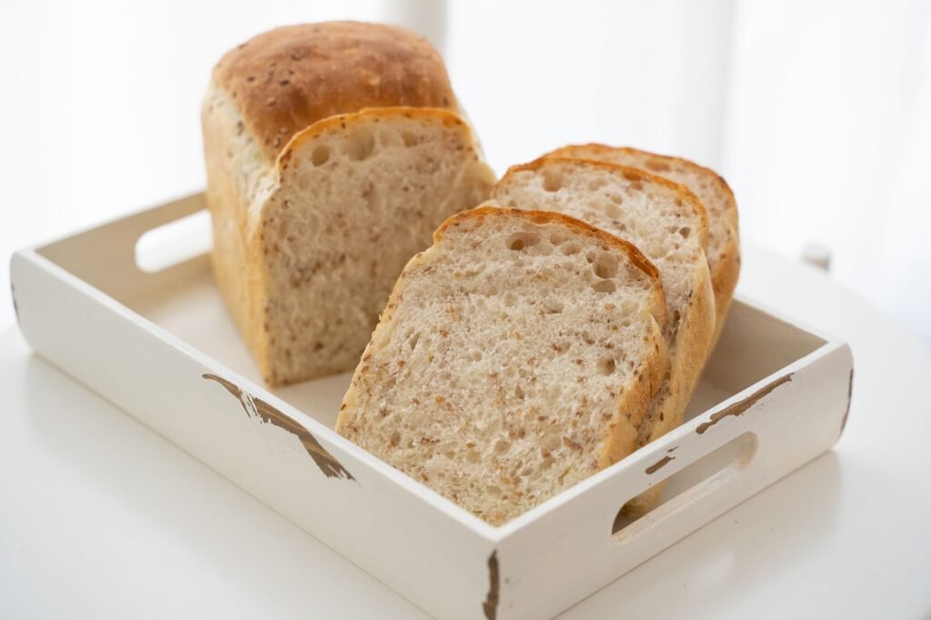 Close-up of freshly sliced homemade bread on a rustic white tray, perfect for breakfast.