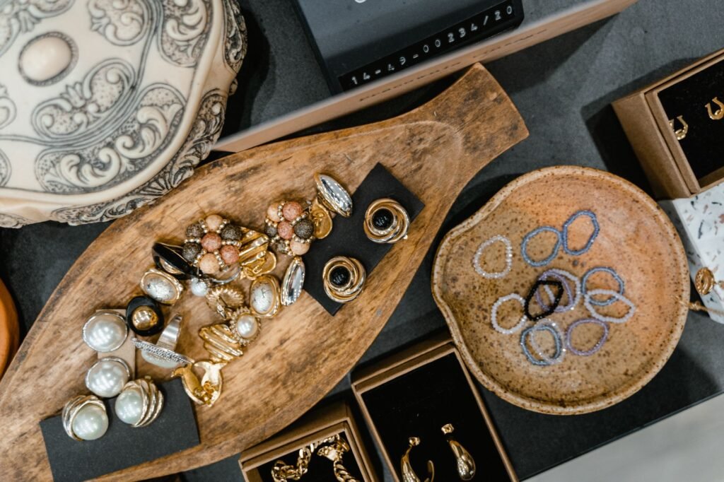 A top view of assorted jewelry including rings and bracelets in a wooden tray and ceramic dish