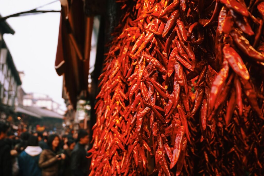 Close-up of red chili peppers in a vibrant street market with bustling crowd