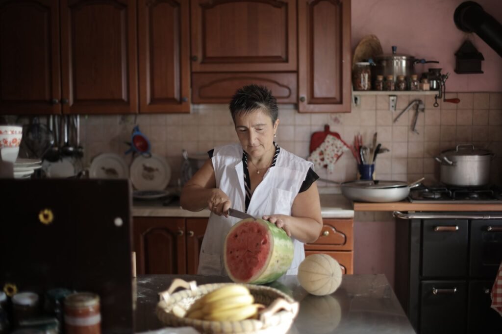 A woman slices watermelon on a kitchen counter, creating a warm and cozy atmosphere