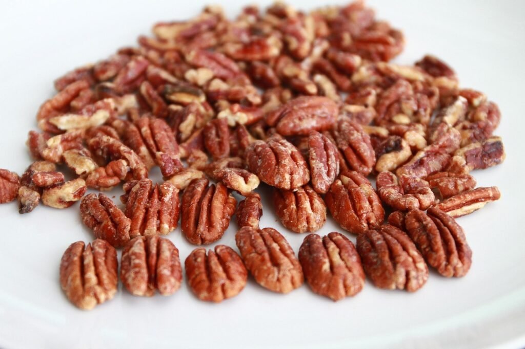 Pile of pecan halves spread across a clean white surface