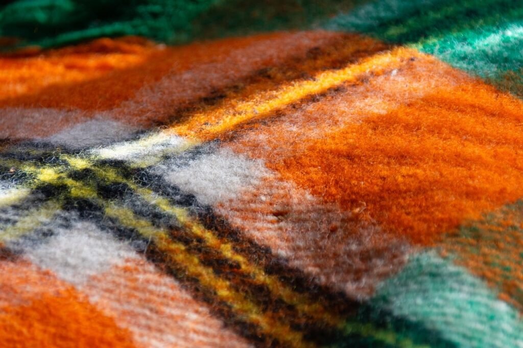 Close view of a soft plaid wool blanket in orange, green and cream